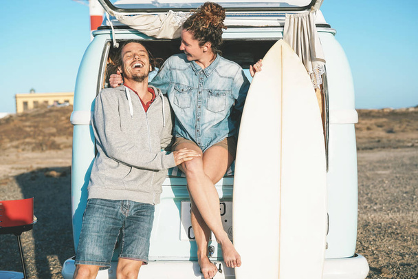 Ζευγάρι ευτυχισμένο surfers στέκεται πίσω από στην mini van vintage τροχόσπιτο - νέοι adventuring για οδικό ταξίδι με ένα minivan μεταφορών - έννοια του ταξιδιού, τις διακοπές, σχέση και νεολαία τρόπου ζωής - Φωτογραφία, εικόνα