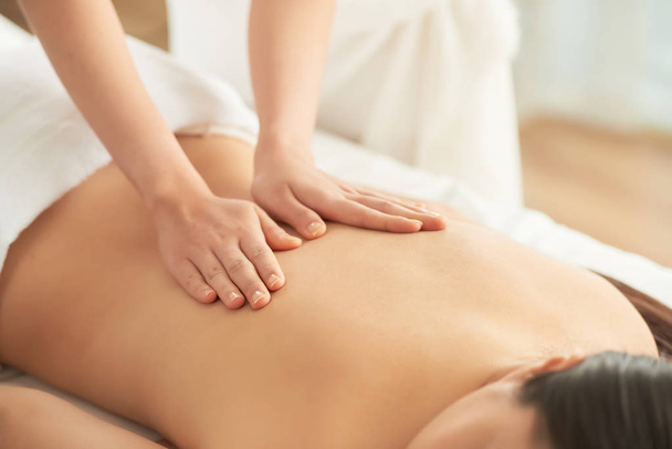 Ernte Hände der Therapeutin massieren Rücken einer nicht erkennbaren Kundin im Wellness-Salon - Foto, Bild
