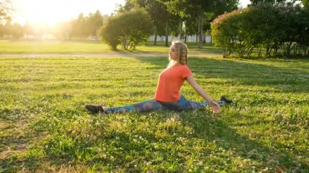 Artistic gymnast sits on the longitudinal and transverse splits. Stretching in the city park - Footage, Video