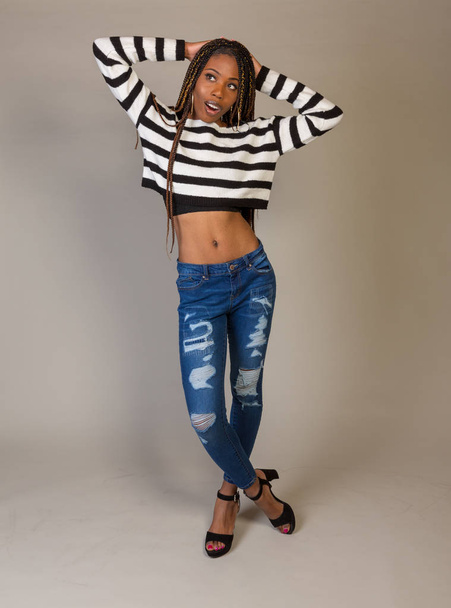 Young Black Girl in striped shirt with exposed midriff posing in studio - Фото, изображение