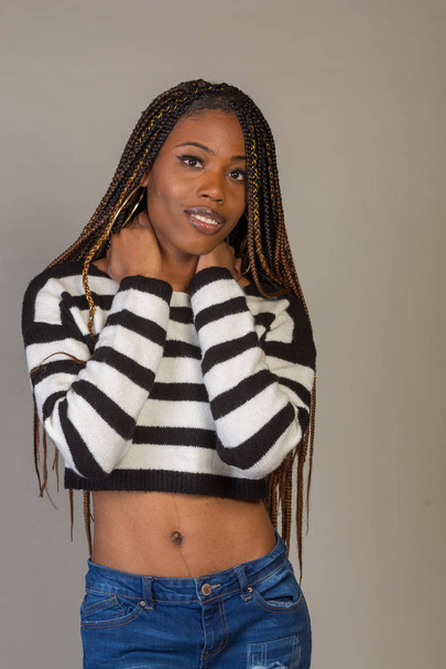 Young Black Girl in striped shirt with exposed midriff posing in studio - Fotó, kép