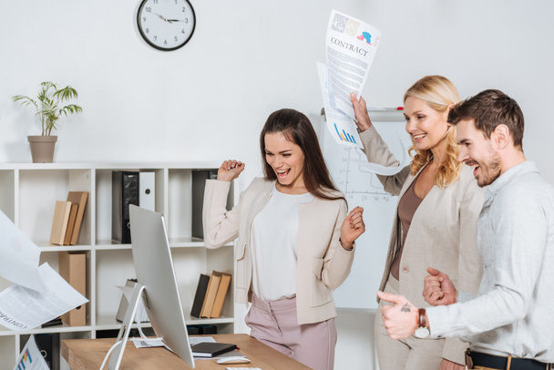 excited businesspeople shaking fists and looking at desktop computer in office  - Photo, Image