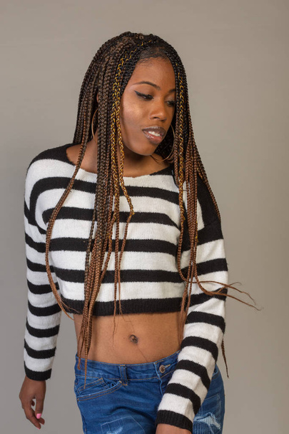 Young Black Girl in striped shirt with exposed midriff posing in studio - Фото, изображение