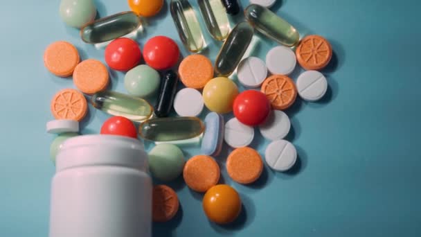 Pilules, comprimés et capsules de médicaments pharmaceutiques assortis et flacon sur fond bleu
. - Séquence, vidéo