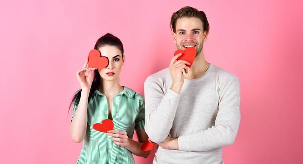 Romantic feelings concept. Valentines day and love. Handsome man and pretty girl in love. Man and woman couple in love hold red heart valentines cards on pink background. Romantic couple in love - Fotoğraf, Görsel