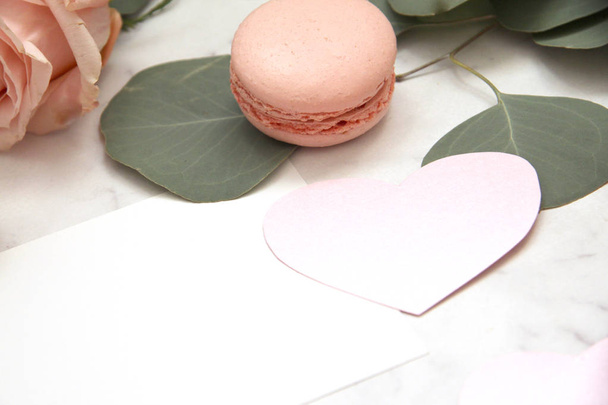 Composition for Valentine's day, pink rose, ribbon, heart, macaroons, eucalyptus, envelope, card, petals - Photo, image
