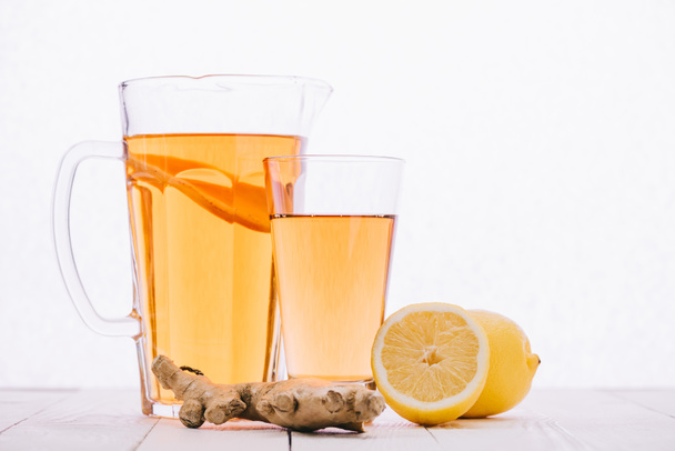 tea citrom és gyömbér gyökér, az üveg és a jar az elszigetelt fehér fa tábla - Fotó, kép