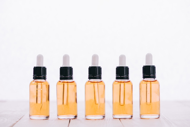 row of cbd oil in bottles with droppers on wooden surface isolated on white - Foto, imagen
