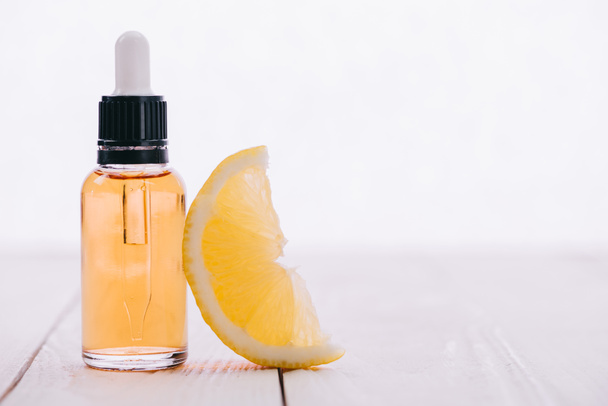 cbd масло в бутылке с капельницей и ломтиком лимона на деревянной поверхности изолированы на белом
 - Фото, изображение