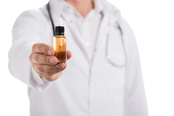 обрезанный вид врача мужского пола, держащего бутылку с жидким маслом в руке, изолированный на белом
 - Фото, изображение