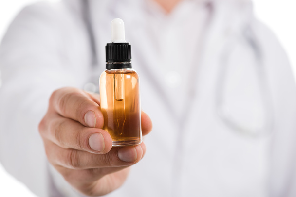 обрезанный вид врача мужского пола, держащего в ручной бутылке эфирное масло, изолированное на белом
 - Фото, изображение