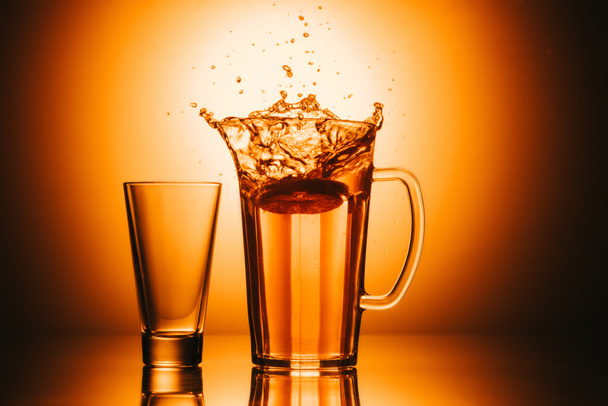 selectieve aandacht van glas en theepot met thee en citroen op een oranje achtergrond - Foto, afbeelding