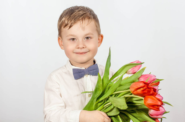 かわいい男の子の花の花束を保持しています。チューリップ。母の日。国際女性の日。幸せな少年の肖像画 - 写真・画像
