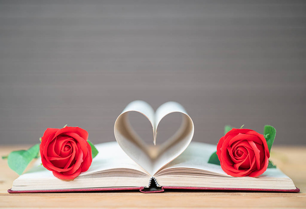 Kitabın sayfaları kalp şeklinde kıvrılmış ve kırmızı gül, aşk konsepti kitap sayfalarından kalp şeklinde. - Fotoğraf, Görsel