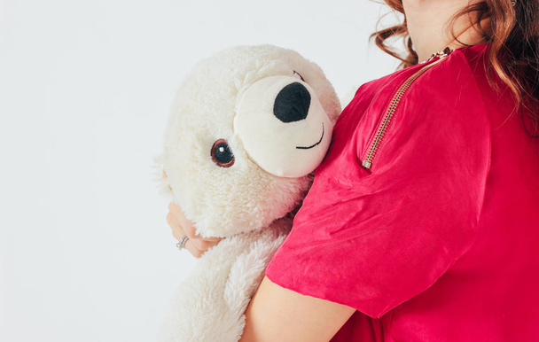 Polar bear toy on hands of young woman in bright pink dress on gray background isolated, concept of Valentine's day - Photo, Image