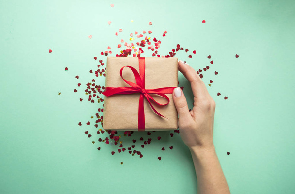 Caja de regalo atada con cinta roja sobre fondo rosa pastel
. - Foto, imagen