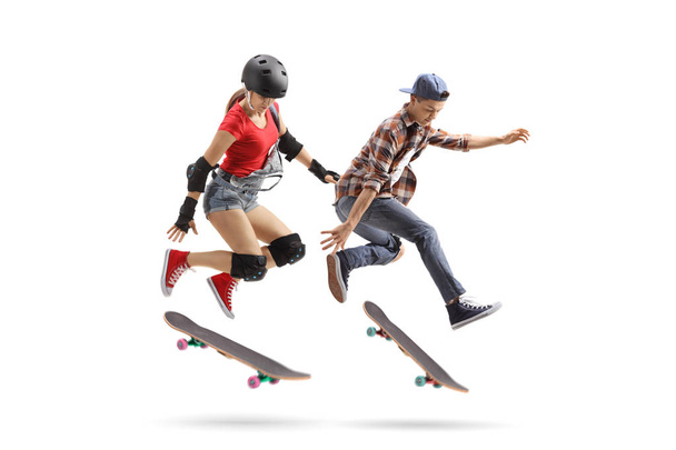 Full length shot of female and male skaters performing a trick with a skateboard isolated on white background - Photo, Image