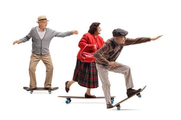 Full length profile shot of a group of seniors riding longboards isolated on white background - Foto, Imagen