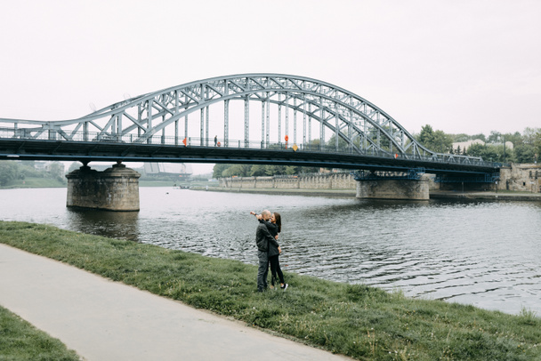 junges verliebtes Paar steht auf der Hängebrücke und umarmt einander lächelnd - Foto, Bild