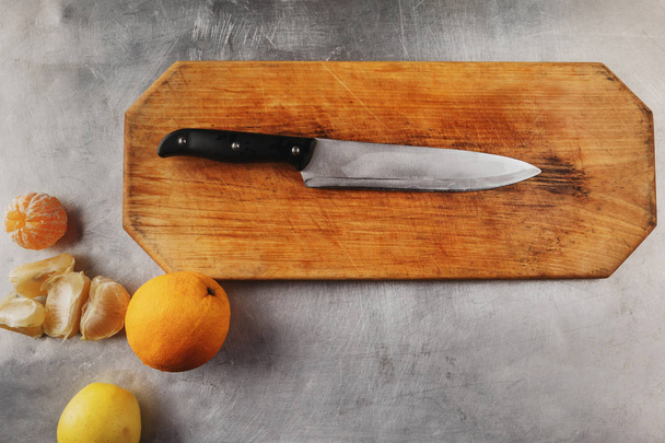 knife on a wooden cutting board. background from an iron professional kitchen table. top view - Foto, Imagen