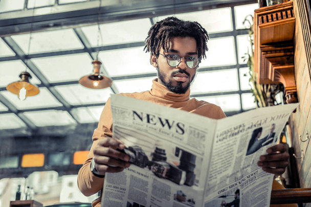 Concentrated brunette man reading attentively world news - 写真・画像