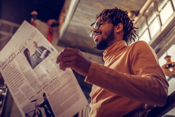 Positive delighted bearded man reading world news - Photo, image