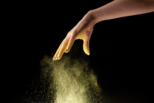 cropped view of woman dropping yellow holi powder on black background - Photo, Image