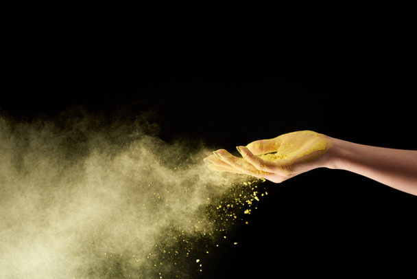 cropped view of adult woman with yellow holi powder on black background - Foto, afbeelding