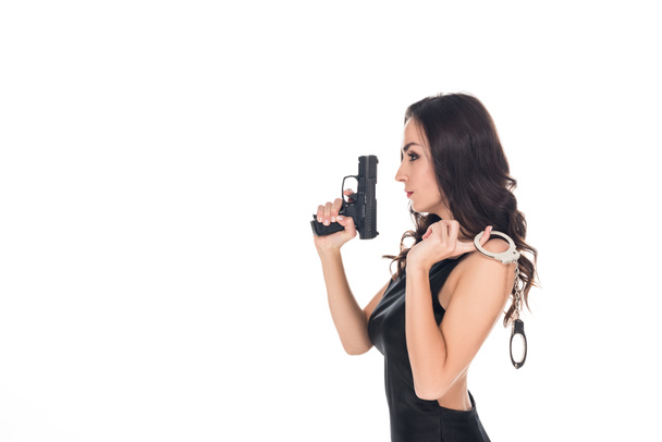elegant security agent in black dress holding handgun and handcuffs, isolated on white - Foto, imagen