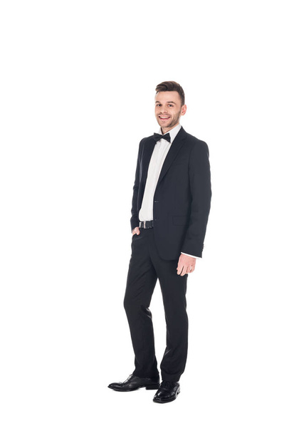handsome smiling man posing in black tuxedo and tie bow isolated on white - Фото, изображение