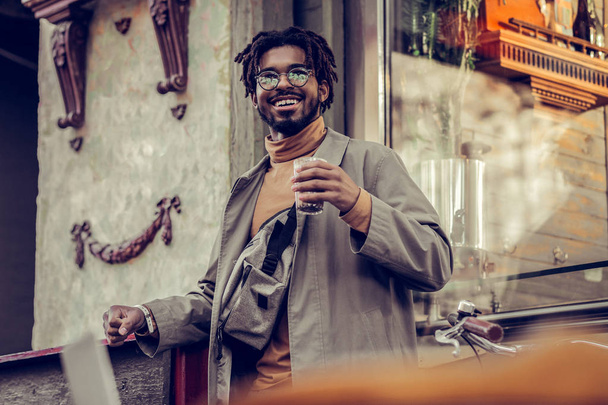 Pleased brunette man drinking cacao in city center - 写真・画像
