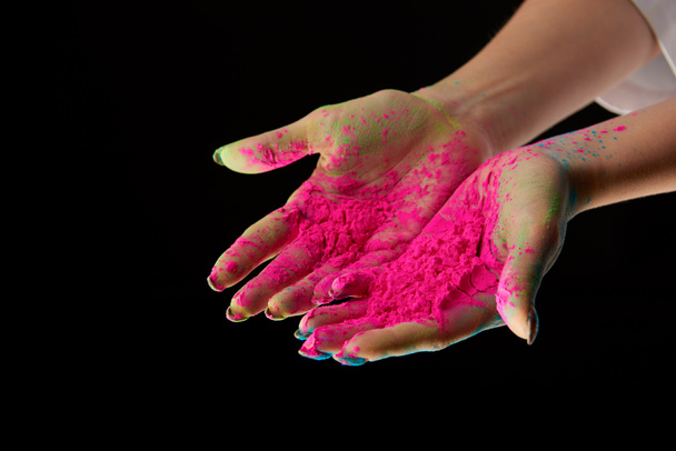 περικοπεί προβολή της ενήλικης γυναίκας, με σκόνη holi ροζ σε χέρια που απομονώνονται σε μαύρο - Φωτογραφία, εικόνα