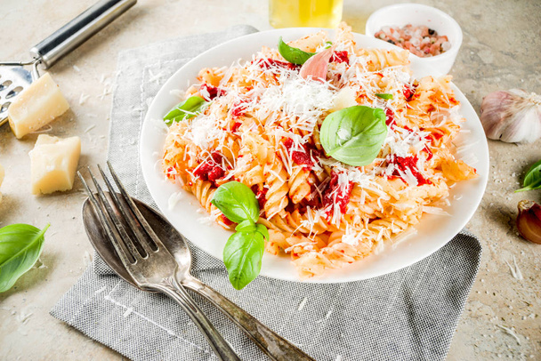 Italian food, fusilli pasta with  tomato sauce, grated parmesan cheese and basil, light stone table copy space top view - Zdjęcie, obraz