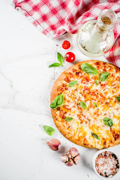 Caseiro fatiado cheesy clássico italiano pizza com ingredientes e azeite, fundo de mármore branco espaço de cópia vista superior
 - Foto, Imagem