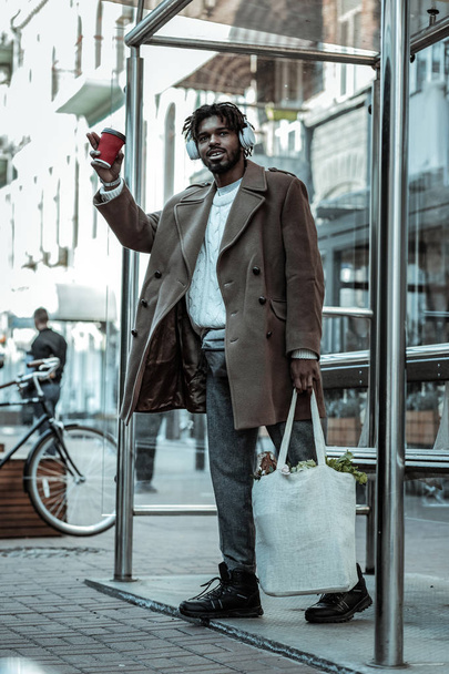 Cheerful brunette male person holding paper cup - 写真・画像
