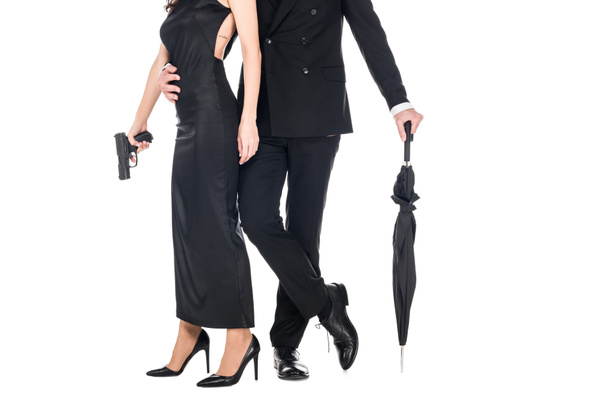 cropped view of couple of killers in black clothes holding gun and umbrella, isolated on white - Fotografie, Obrázek