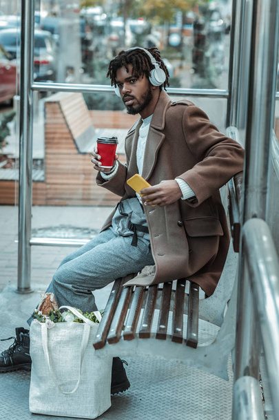 Being late. Cheerful student wearing headphones while going to drink coffee - Fotoğraf, Görsel