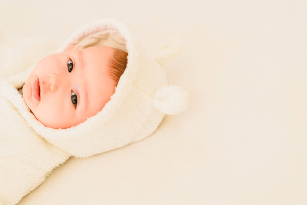 Baby girl lying on a white bed, adorable looking at camera. - Photo, Image