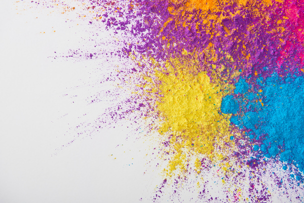 vista dall'alto di esplosione di giallo, viola, arancione e blu holi polvere su sfondo bianco
 - Foto, immagini