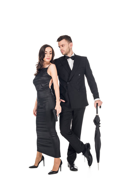 beautiful couple of killers in black clothes posing with gun and umbrella, isolated on white - Zdjęcie, obraz