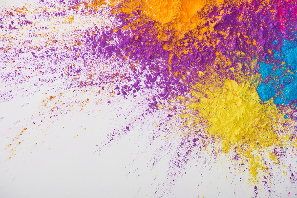 vista superior de la explosión de polvo de holi amarillo, púrpura, naranja y azul sobre fondo blanco
 - Foto, Imagen