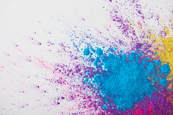 top view of explosion of yellow, purple and blue holi powder on white background - 写真・画像