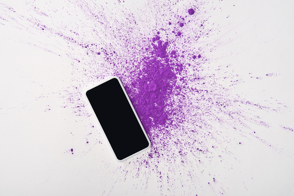 top view of smartphone with blank screen and explosion of purple holi powder on white background - Photo, Image