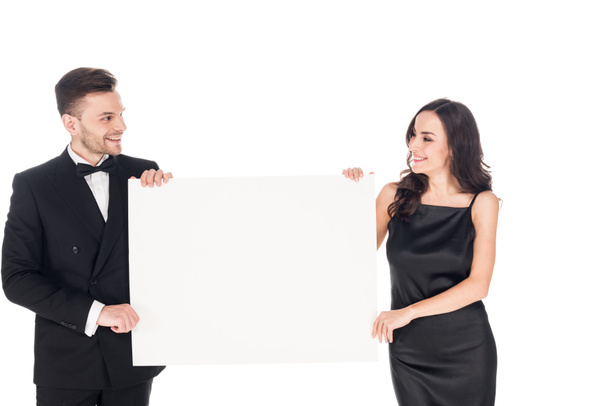 attractive couple in black elegant clothes holding empty board, isolated on white - Фото, изображение