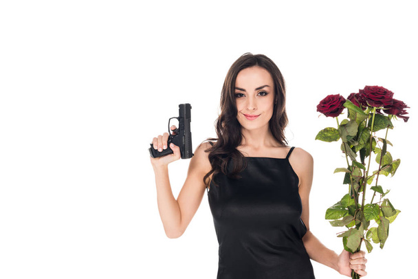 schön lächelnder Geheimagent mit Handfeuerwaffe und roten Rosen, isoliert auf weiß - Foto, Bild