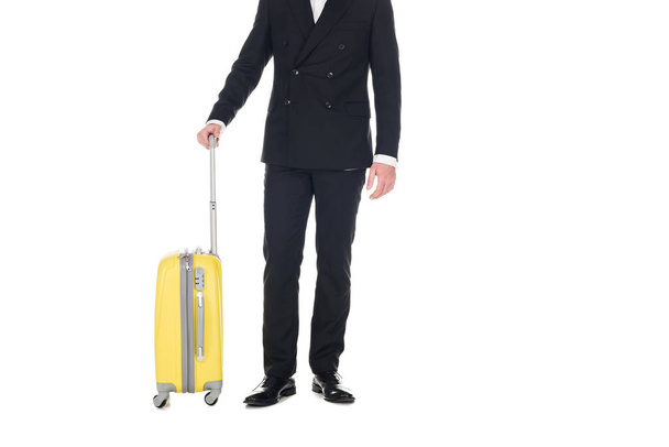 cropped view of man in black tuxedo posing with travel bag isolated on white - Фото, изображение