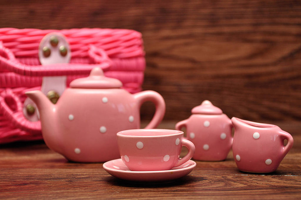 Un juego de té manchado de porcelana con una canasta rosa
 - Foto, Imagen