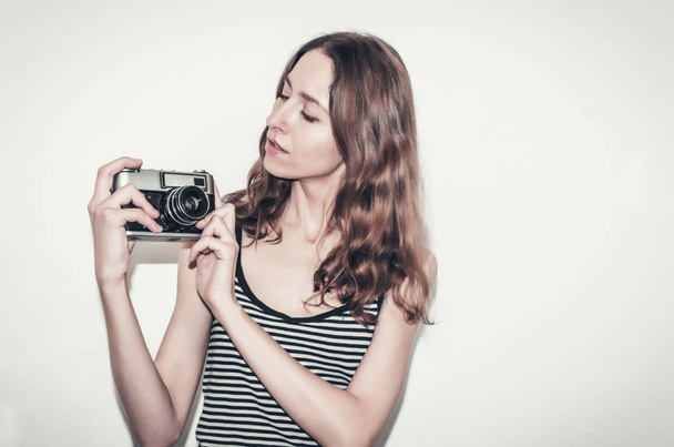 Nice girl in a striped t-shirt with  vintage camera in her hands. Photographing people. - Fotó, kép