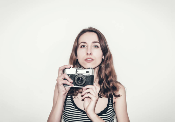 Linda chica con una camiseta a rayas con cámara vintage en sus manos. Fotografiar personas
. - Foto, imagen