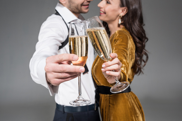 selective focus of couple clinking with champagne glasses isolated on grey - Fotoğraf, Görsel